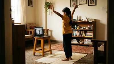 A young child following a coach on a laptop screen in a sunlit Indian living room